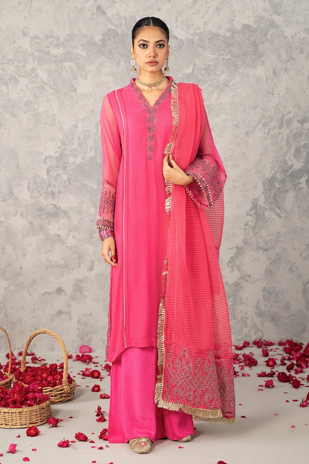 A woman wearing a medium-size Charizma pink embroidered 3PC poly net suit – a stylish choice for Pakistani suits online in Canada.