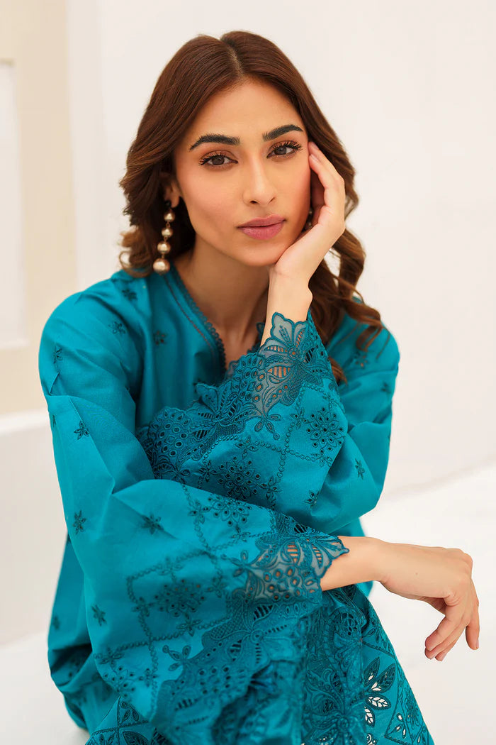 women sitting showing detailed close-up of the intricate embroidery on Baroque’s sea green lawn suit – a refined choice for Pakistani fashion lovers.