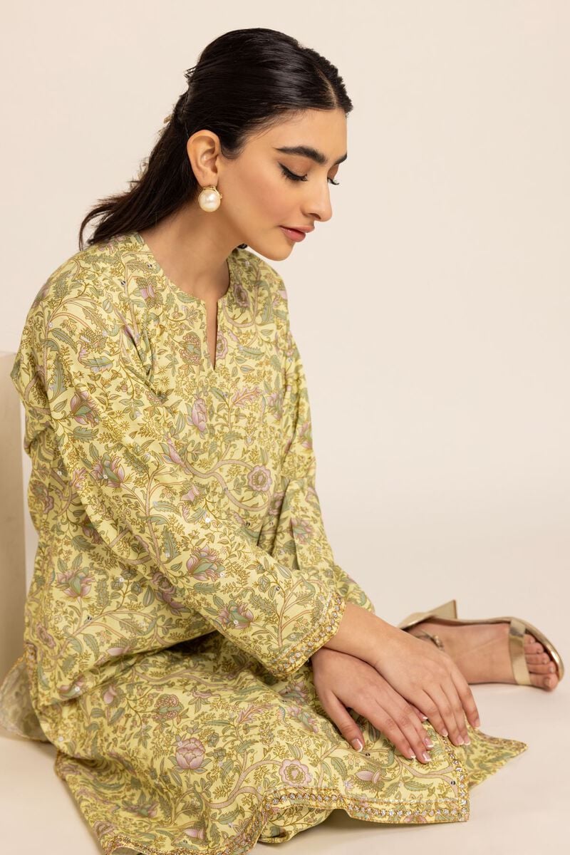 A LADY SITTING view of Khaadi’s floral embroidered kurta, offering a comfortable yet stylish look in Pakistani fashion.