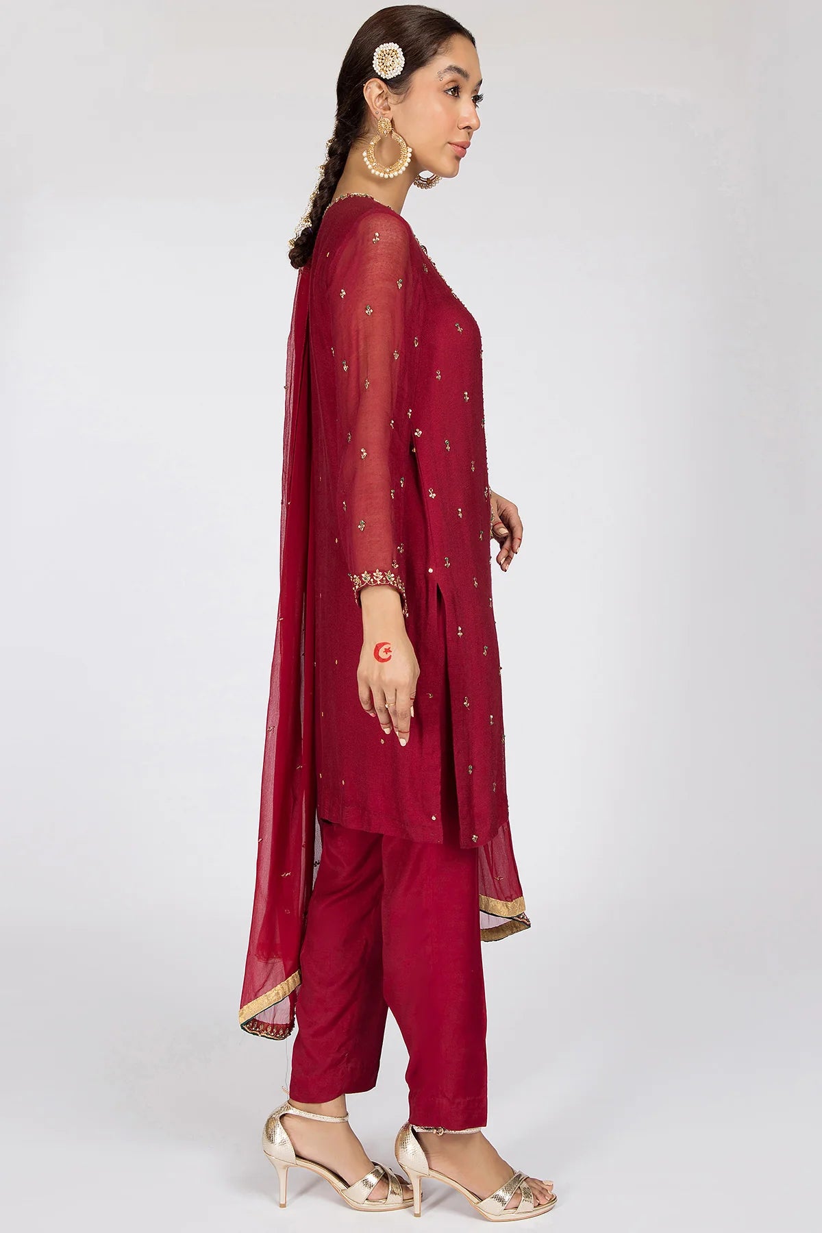 Side profile of Kayseria’s maroon silk net suit, highlighting its intricate embellishments and premium raw silk trousers