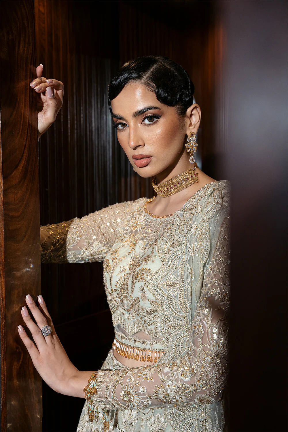 Close-up detail of Pakistani bridal dress featuring intricate Chinese Silver embroidery, gold accents, and traditional choker necklace, highlighting the premium craftsmanship and fabric texture
