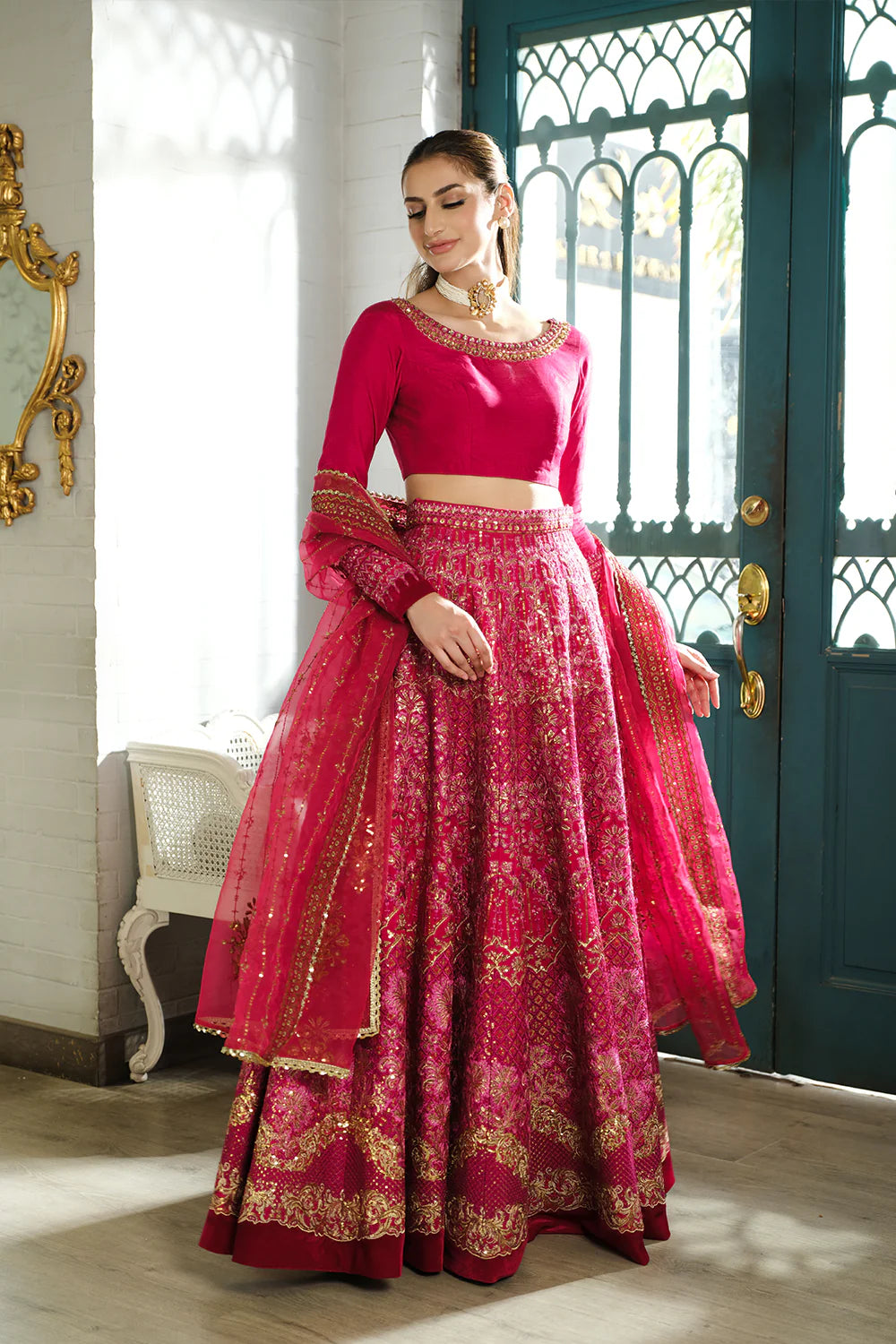 Saira Rizwan bridal lehenga elegant pose - fuchsia pink Korean silk choli with gold embroidered lehenga.