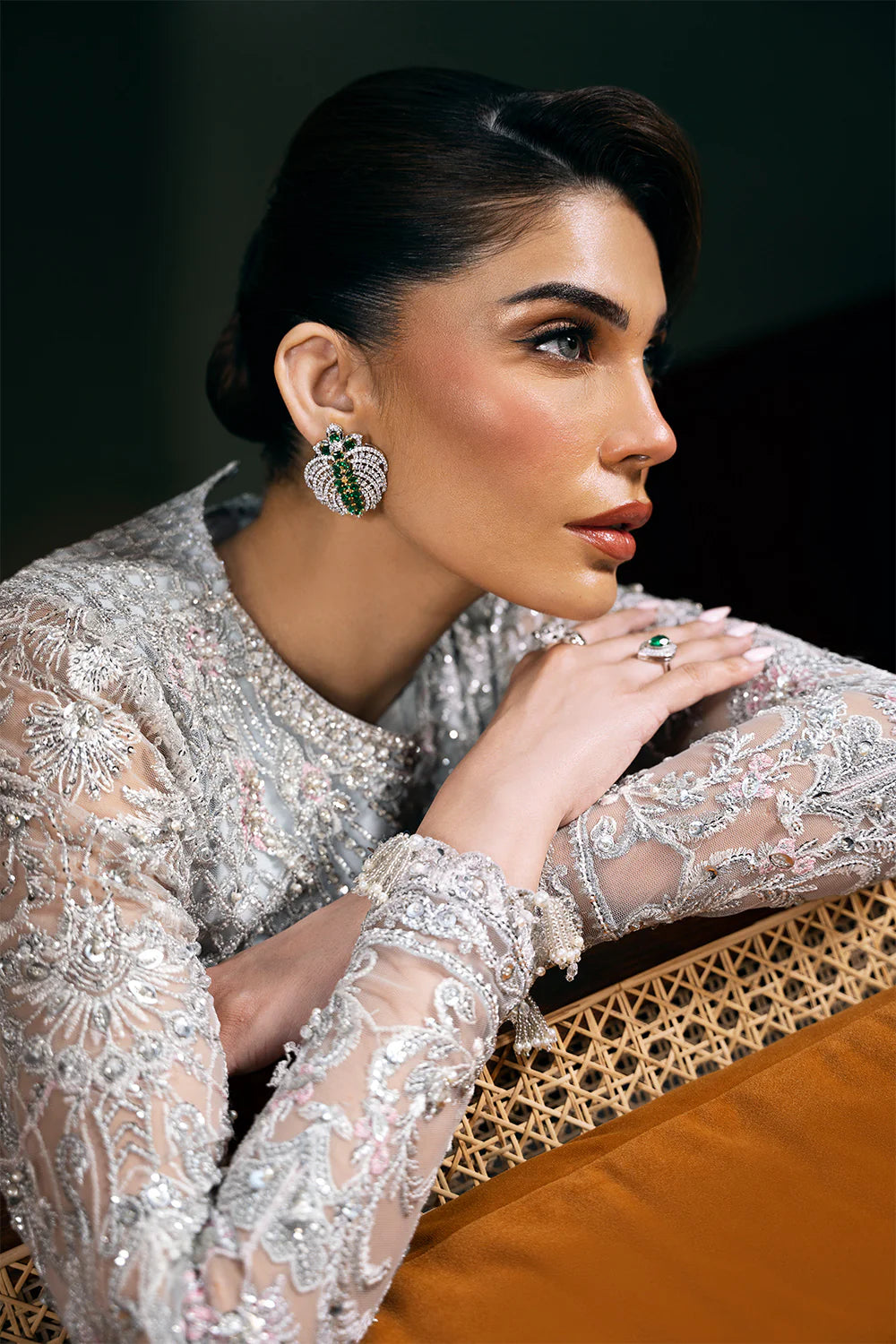 Profile view of model in Saira Rizwan grey bridal outfit with traditional statement earrings and sheer embroidered net fabric sleeves