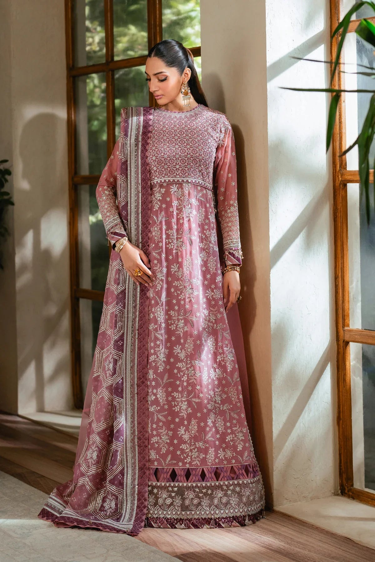 Woman standing leaning by window Xenia luxury embroidered chiffon Pakistani suit mauve festive Eid wedding Canada Tarz-e-Mashriq