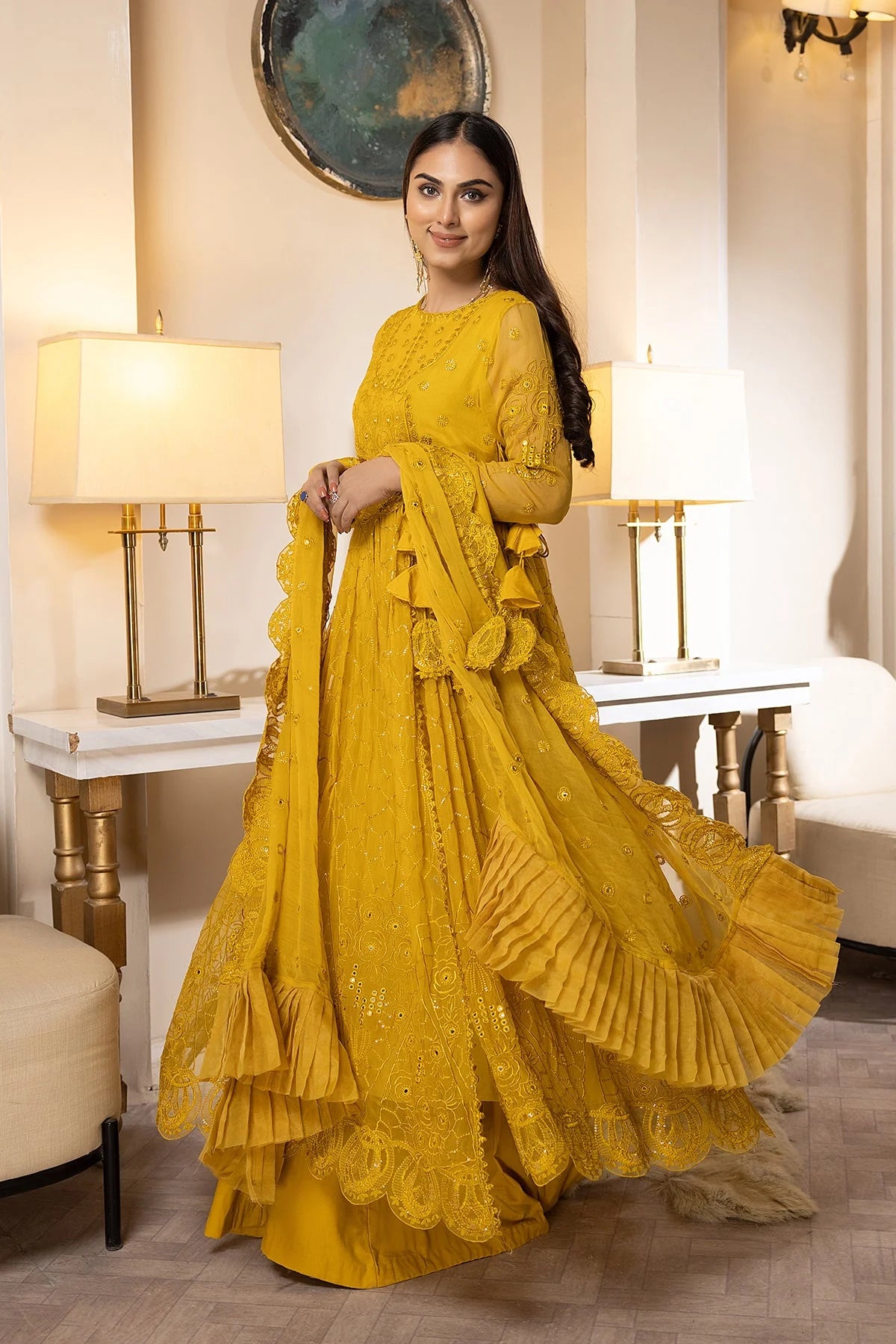 A woman wearing a yellow embroidered chiffon maxi with a silk sharara, a luxurious choice for Pakistani suits online in Canada.