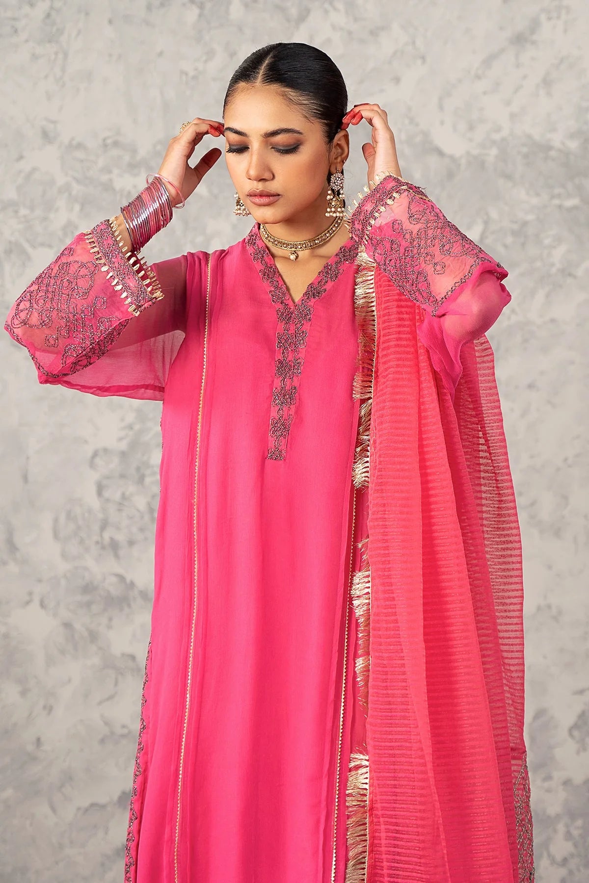 Punjabi suits in Canada – A woman in a Charizma pink poly net suit, highlighting its fine craftsmanship and rich fabric texture.