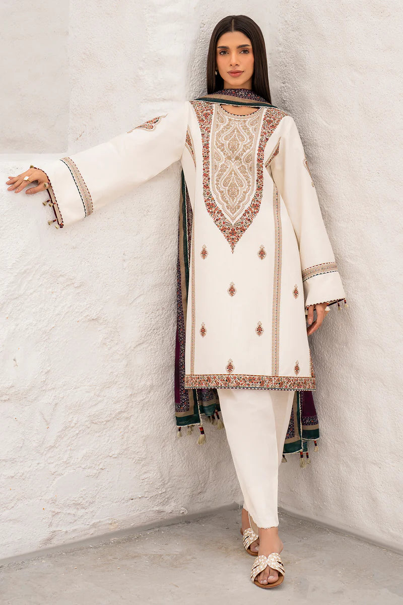 Woman wearing a white embroidered traditional outfit of Indian dresses against a white wall 