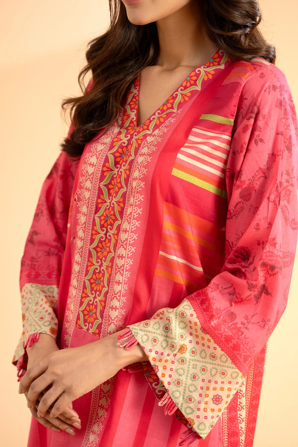 women showing the Close-up of Charizma’s printed lawn fabric – showcasing high-quality stitching and vibrant colors for premium Punjabi suits.