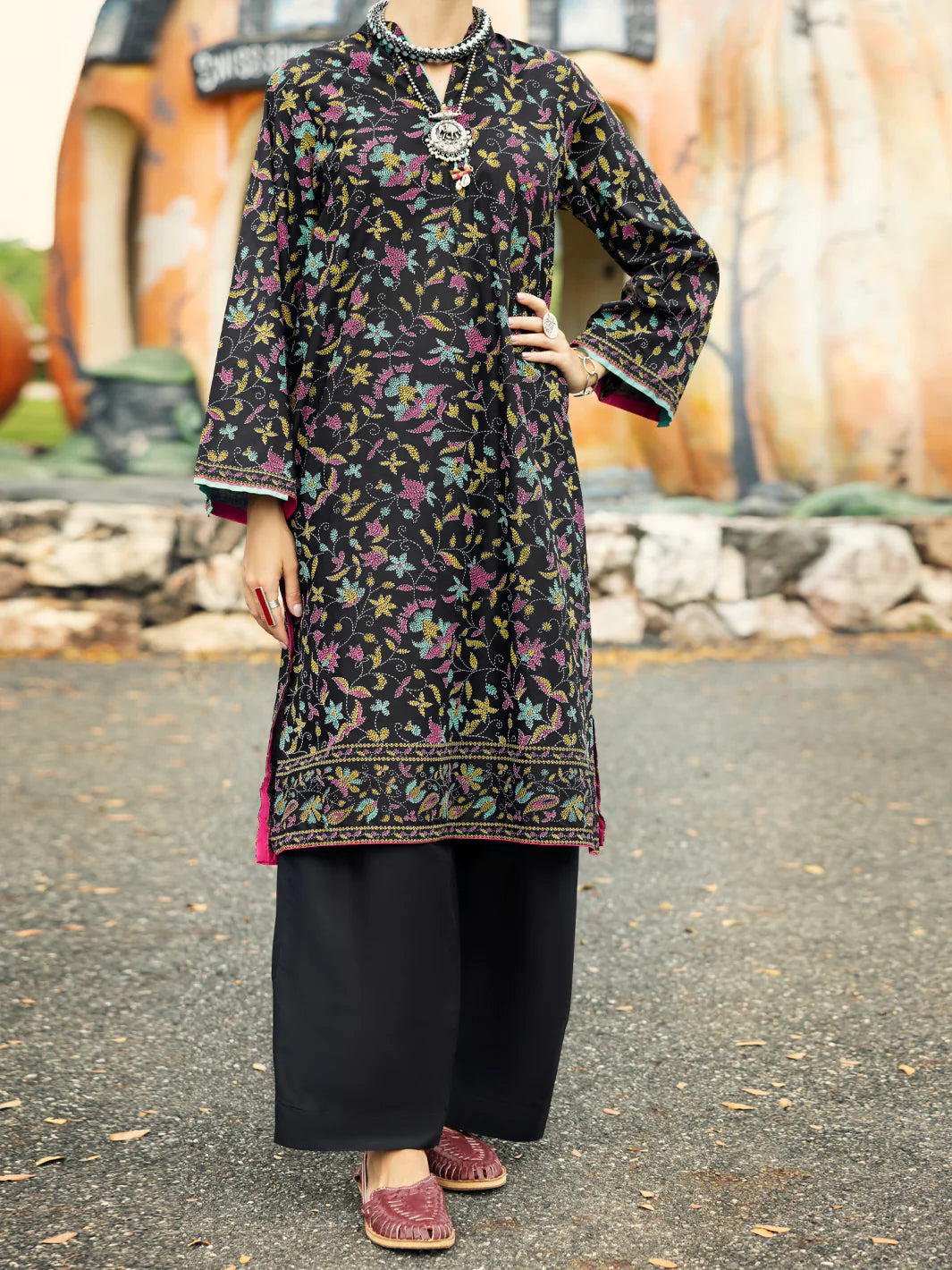 Woman standing front view full length hand on hip black floral lawn kurti tassel neckline embroidered hem Almirah Eid Pakistani suits Canada