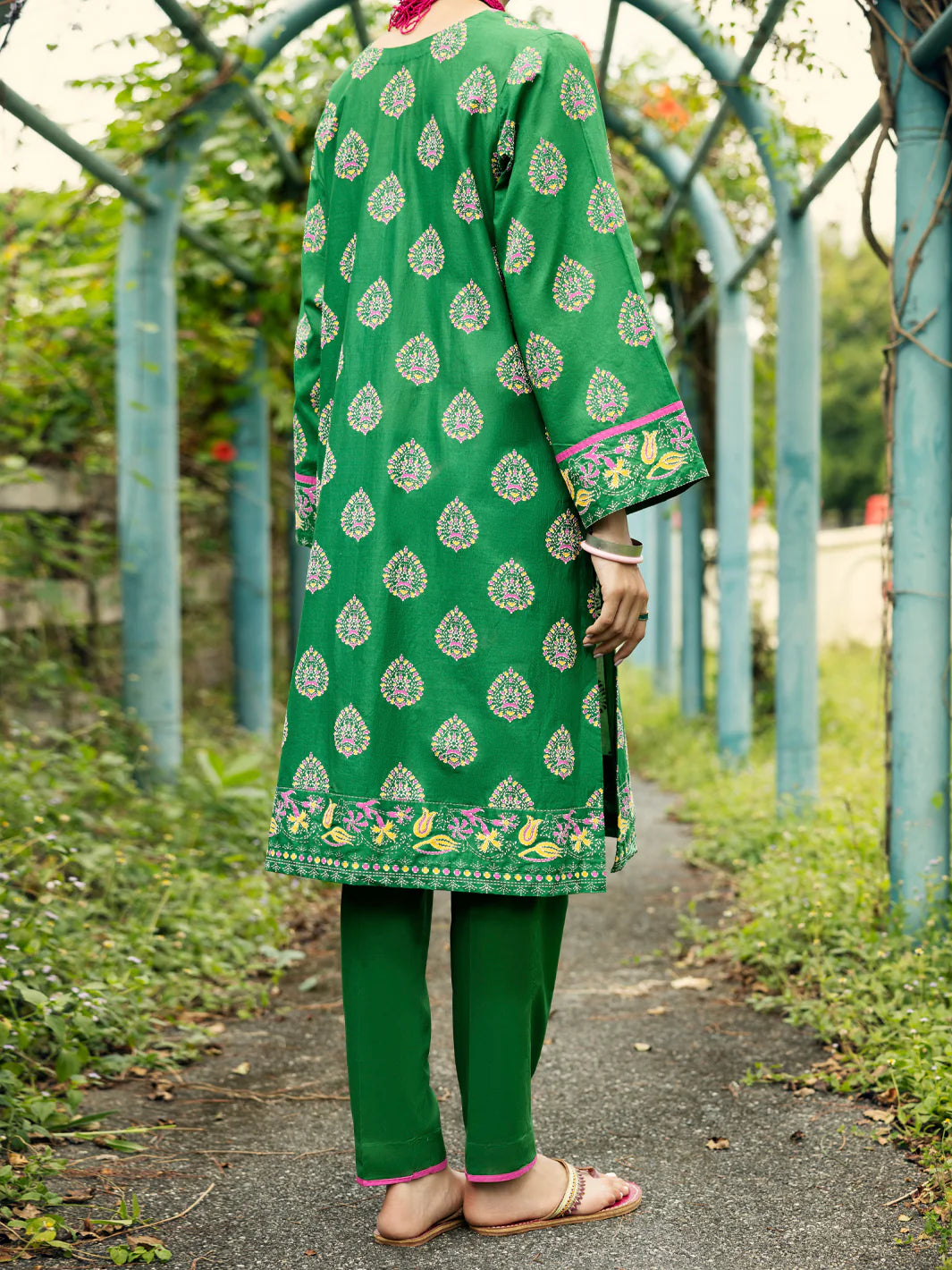 Woman standing back view full length emerald green paisley print lawn kurti embroidered hem border bell sleeves Almirah Diwali Pakistani suits Canada