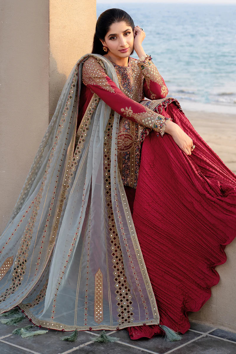 Woman in traditional red and gold outfit by the sea in sitting position with sea in the background showing Punjabi dresses in Canada online