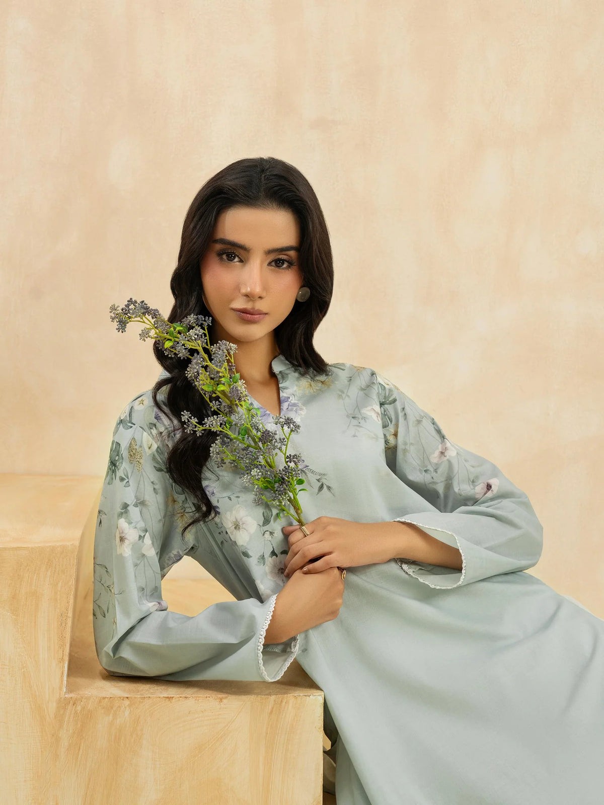 Woman sitting 3-quarter view steps holding flowers sky blue printed cambric casual top Limelight Eid Pakistani suits Canada women