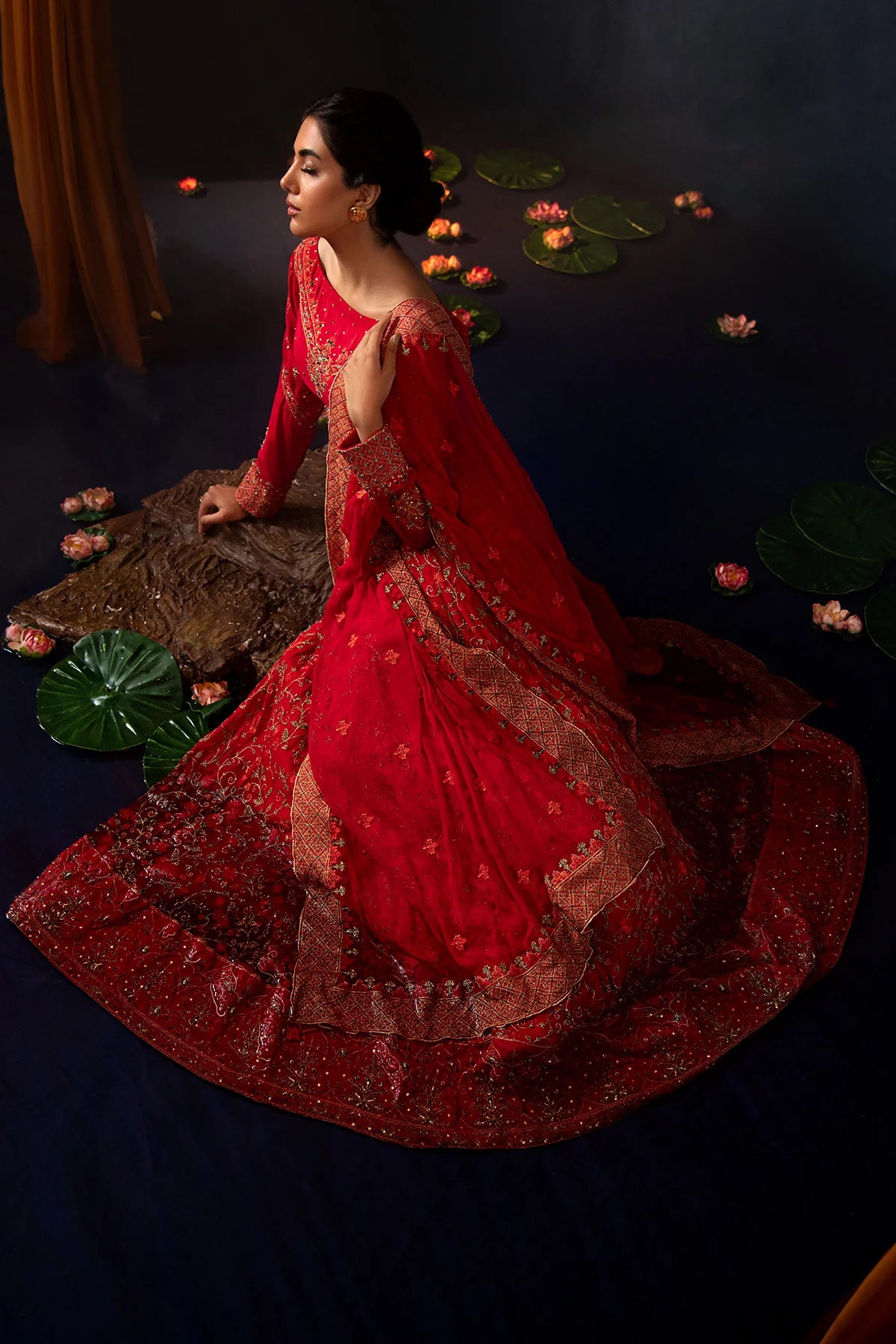women sitting wearing Kayseria’s maroon 3PC suit, highlighting the detailed embellishments on the kurti and lehenga.