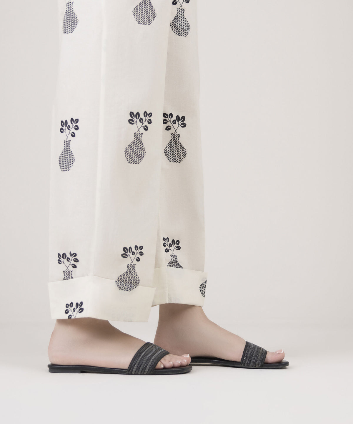 Woman side close-up Sapphire off-white Pakistani suits cambric straight pants vase leaf cuff slit hem festive