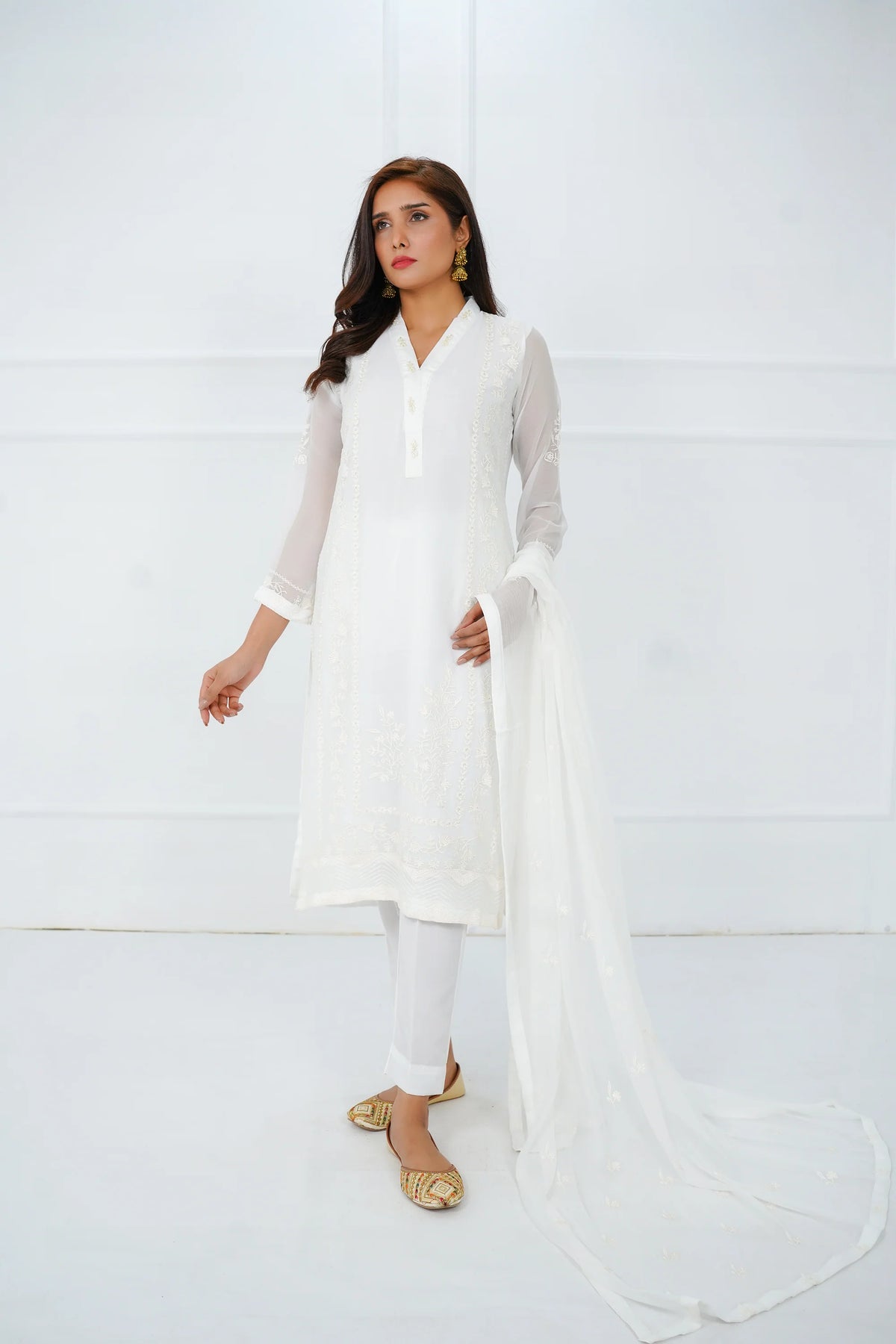 A woman wearing a classic black 3-piece stitched suit with embroidery, consisting of a chiffon shirt, dupatta, and trousers.