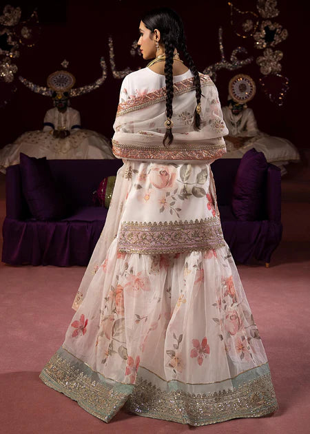Back view of white floral sharara set showcasing intricate gold border work, floral print details, and traditional Pakistani outfit silhouette