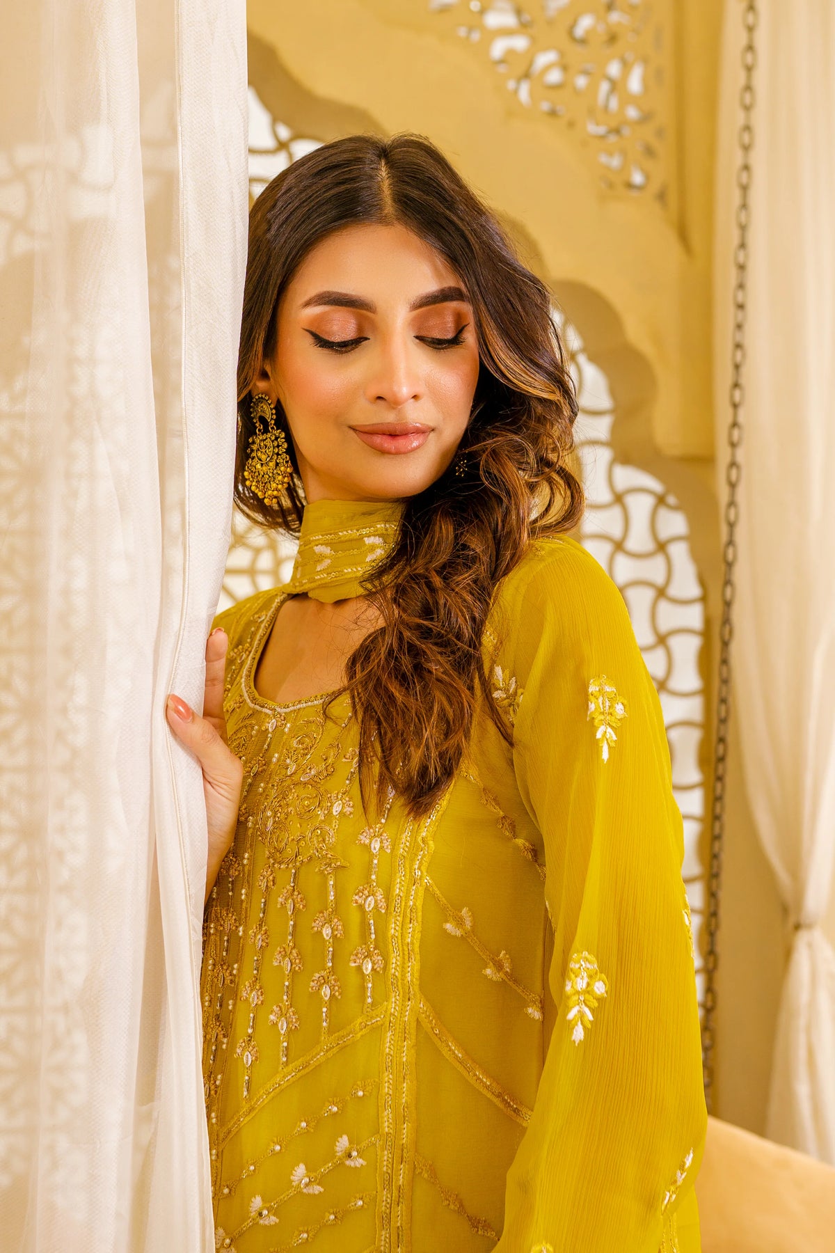Woman standing with curtain wearing mustard chiffon Pakistani suit Canada Sheep brand hand embellished Eid wedding women